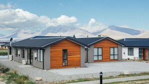 Une rangée de chalets modernes aux grandes fenêtres et aux éléments décoratifs en bois, se dressant sur fond de montagnes.