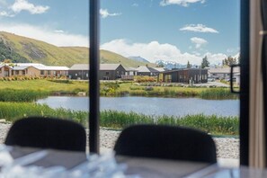A view of a hotel with multiple buildings, a pond, and mountains in the background.
