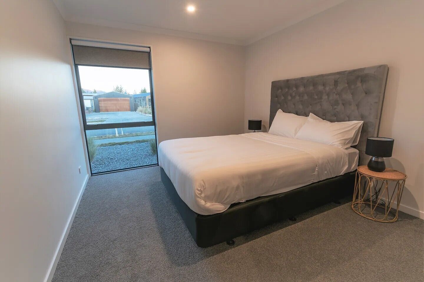 Un dormitorio moderno con una cama grande, una mesita de noche y vistas a un espacio exterior por una puerta corrediza.