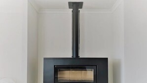Un poêle à bois moderne doté d’une porte en verre, d’un conduit de cheminée et d’un cadre noir.