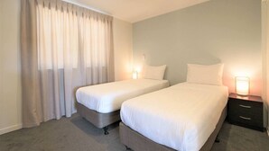 A hotel room with two single beds, a nightstand with a lamp, and a large window with curtains. - Jeros 2bdr Apartment (Lake Tekapo)