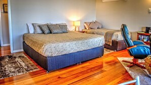 A bedroom with a large bed, a smaller bed, a desk with a chair, and an air conditioning unit. - Deluxe King Studio - Cedar (Ocean View)