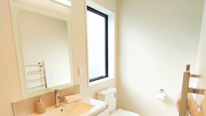 Une salle de bain moderne avec un meuble-lavabo blanc, des toilettes et un grand miroir.