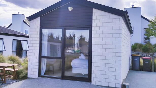 Un bâtiment moderne doté d’une porte et de fenêtres en verre, entouré d’une zone pavée et de quelques espaces verts.