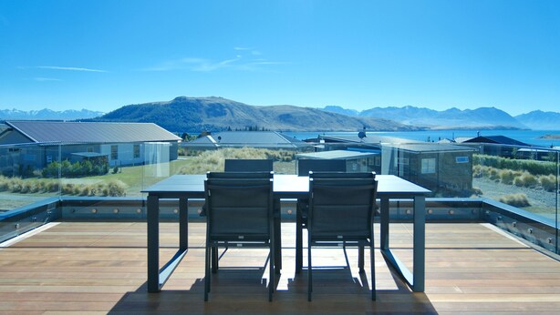 A deck with a table and chairs overlooking a mountainous landscape.