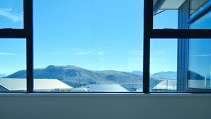 A room with a large window offering a view of mountains and a clear sky.