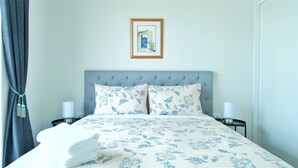 A neatly made bed with a floral bedspread, two matching pillows, and a framed picture on the wall. - Stargazing Tekapo Apartment C (Lake Tekapo)