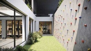 A modern building with a climbing wall and a well-maintained lawn.