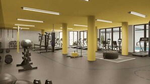 A modern gym with exercise equipment, large windows, and bright lighting.