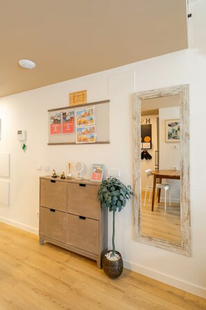 A room with a wooden cabinet, a mirror, and a bulletin board with travel posters. - Studio Home Madrid (San Sebastian De Los Reyes)