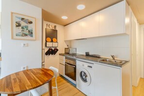 Een kleine keuken met een wasmachine, een magnetron en een spoelbak.