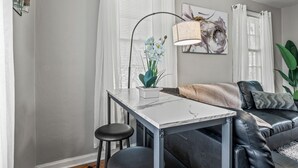 Un salon avec une table en marbre blanc, un canapé en cuir noir et un lampadaire.