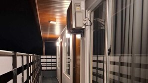 Passadís amb sostre de fusta, barana metàl·lica a un costat i finestra gran a l'altre.
