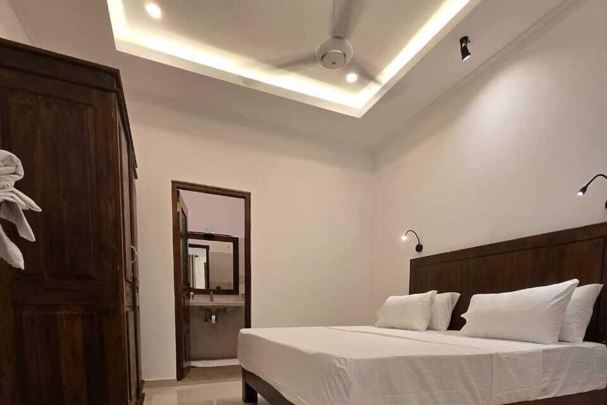 A modern bedroom with a large bed, a ceiling fan, and a wooden wardrobe.