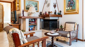 A living room with a fireplace, two armchairs, a coffee table, and a television.