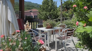 An outdoor patio with a table and chairs, surrounded by potted plants and flowers.