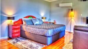 A bedroom with a bed, a nightstand, a lamp, and a chair.