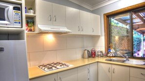 A compact kitchen with white cabinets, a gas stove, a microwave, and a sink.