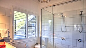 A modern bathroom with a glass shower enclosure, a toilet, and a sink with a towel rack.