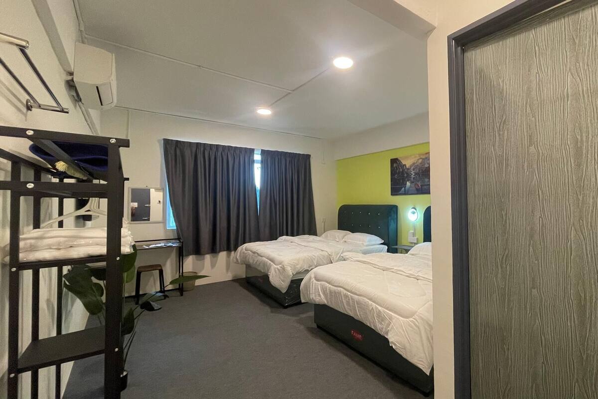 A hotel room with bunk beds, a desk, a chair, a small table, and a door.