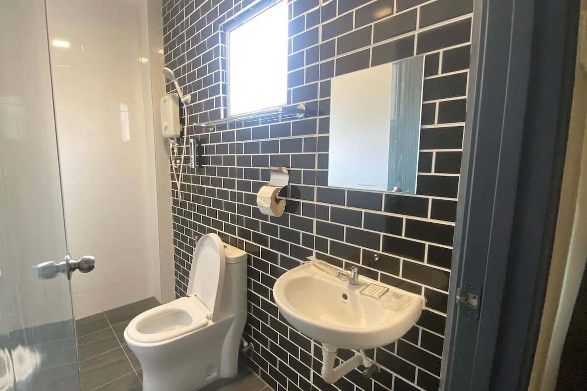 A bathroom with a toilet, sink, and a mirror on the wall.