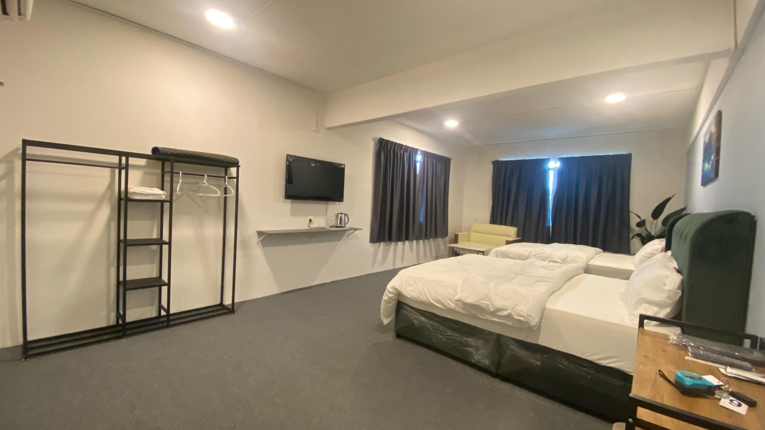 A hotel room with a bed, a desk, a chair, a TV, a wardrobe, and a window with curtains.