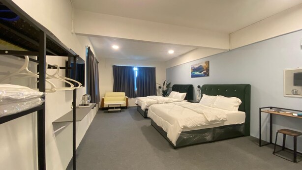 A hotel room with two beds, a chair, a desk, and a mirror. - RAZO VILLAGE INN (Taiping)