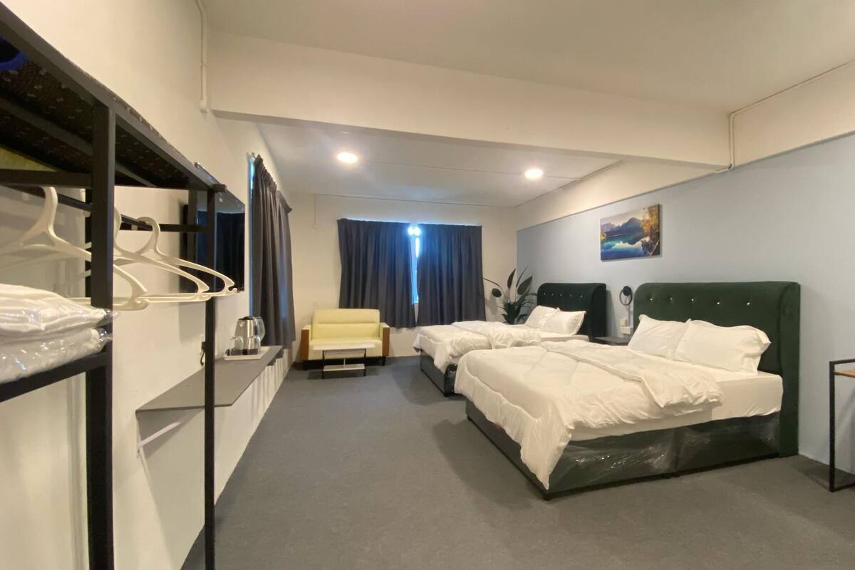 A hotel room with two beds, a chair, a desk, and a mirror.