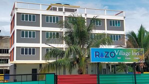 A multi-story building with a sign for RAZO Village Inn, featuring a modern architectural design with balconies and large windows. - RAZO VILLAGE INN (Taiping)