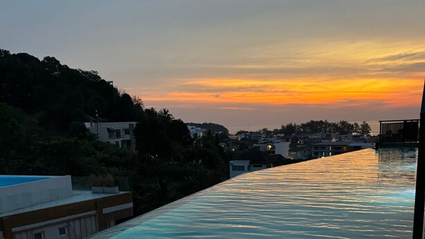 Una piscina con vistas a un atardecer y edificios circundantes.