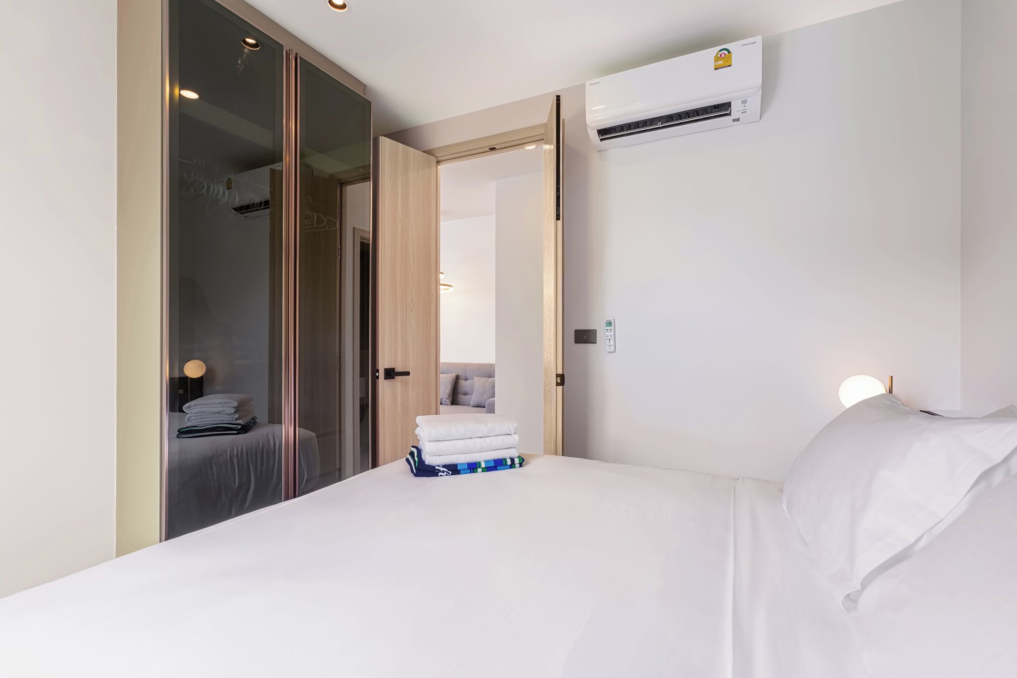 Una habitación de hotel con una cama, un equipo de aire acondicionado, un armario y una lámpara de noche.