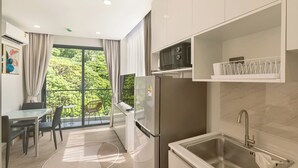 Una cocina moderna con microondas integrado, un lavamanos de acero inoxidable y un comedor con mesa y sillas.
