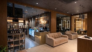 A modern hotel lobby with a reception desk, seating area, and a wine display.