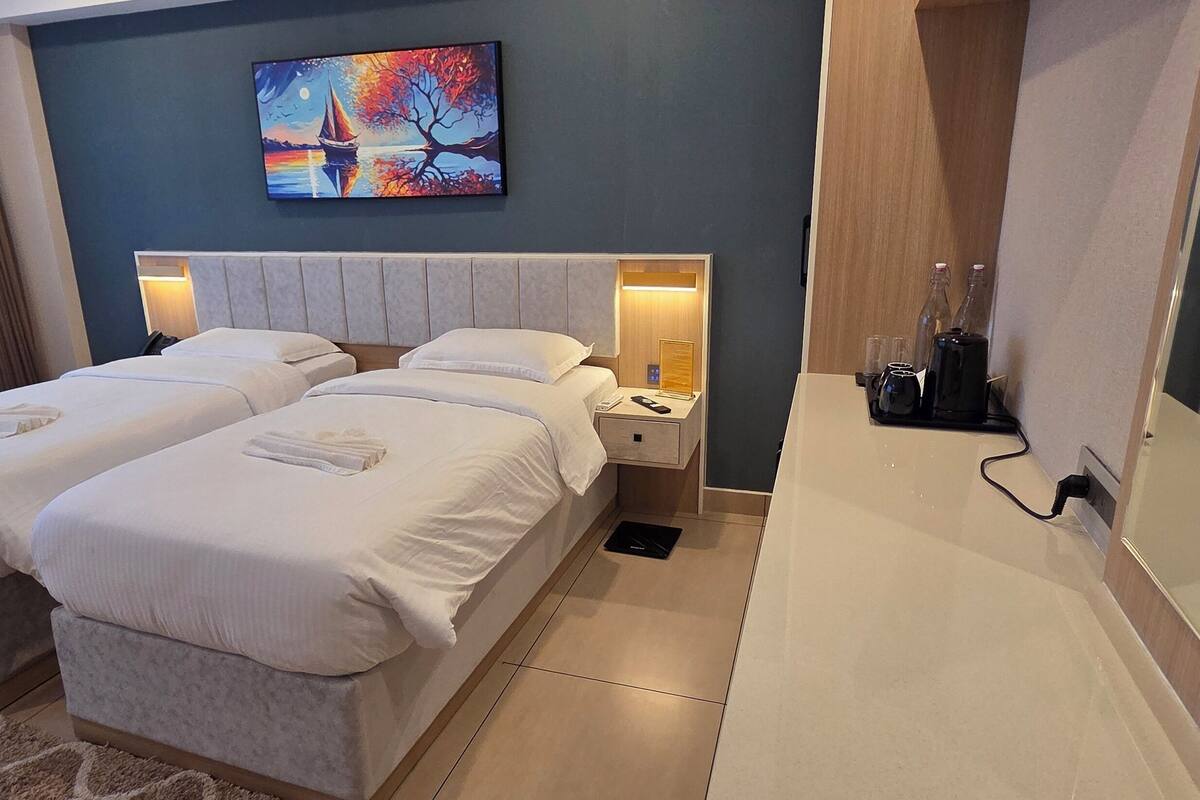 Een hotelkamer met twee bedden, een bureau en een grote spiegel.