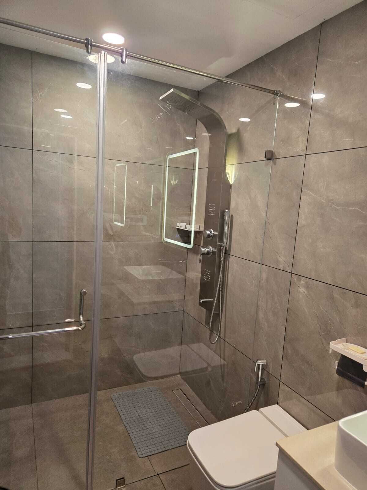 Une salle de bain moderne avec une douche à parois de verre, des toilettes blanches et un lavabo.