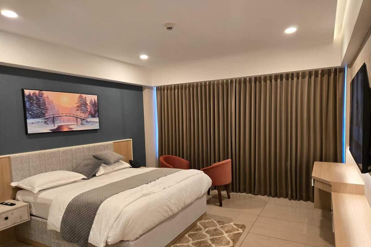 Een moderne hotelkamer met een groot bed, een nachtkastje, een stoel, een televisie en een schilderij aan de muur.