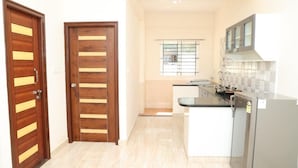 Una cocina con estufa integrada, refrigerador y ventana con reja de metal.