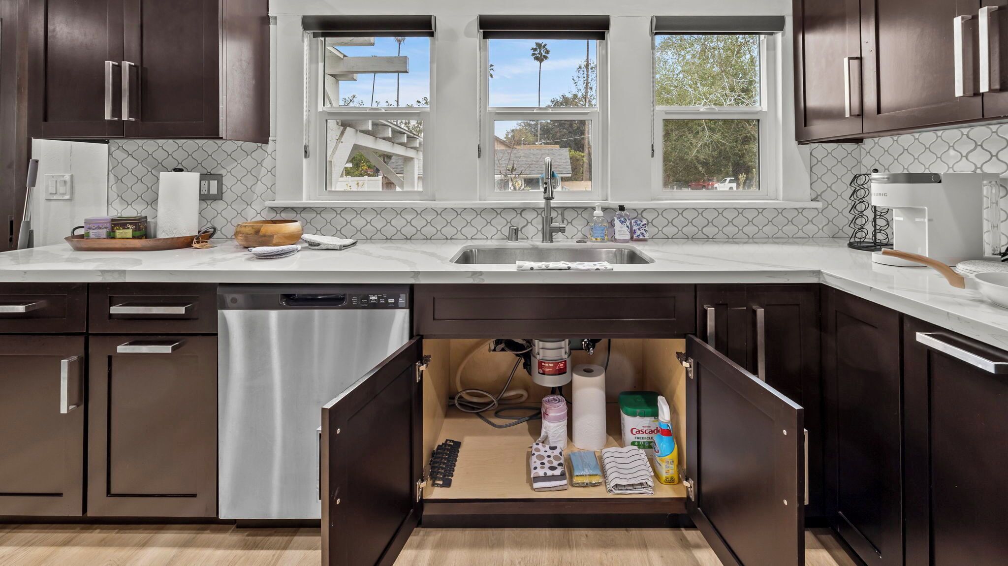 Una cocina moderna con armarios de madera oscura, lavavajillas de acero inoxidable y pileta integrada.