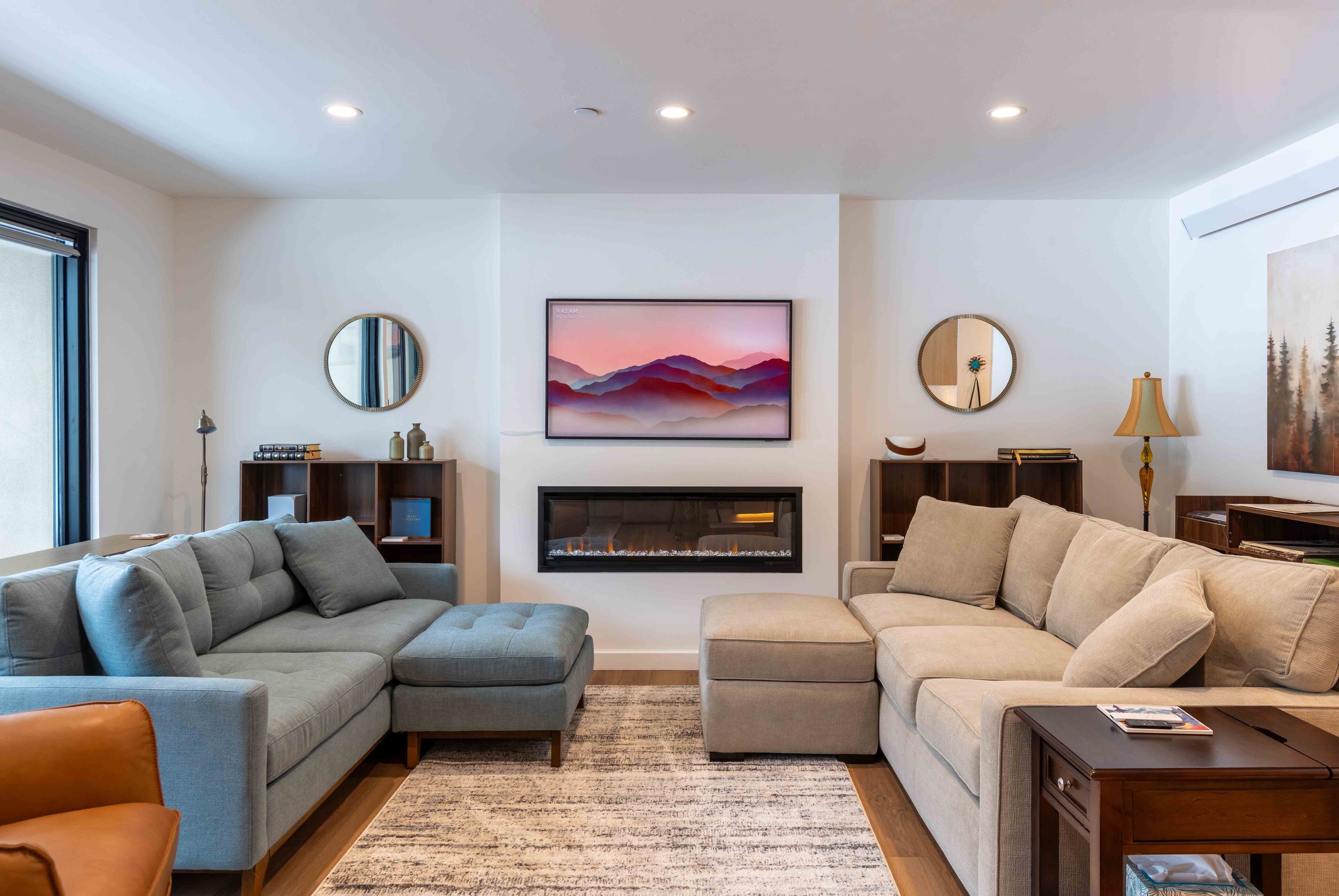 A modern living room with two sofas, a fireplace, and artwork on the walls.