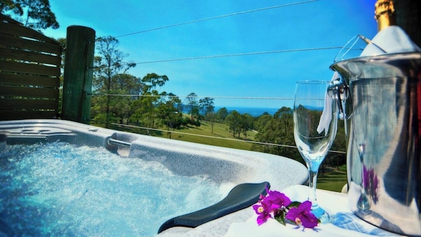 Banheira de hidromassagem com um copo e flores, uma garrafa de champanhe e uma vista panorâmica.