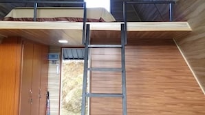 Una habitación con literas, paredes de madera, una escalera y una ventana.