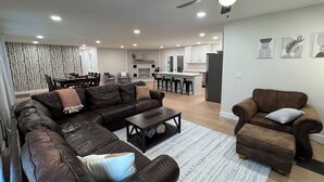 Ein modernes Wohnzimmer mit Ledersofas, einem Couchtisch und einem Essbereich mit einer Chandelieber.