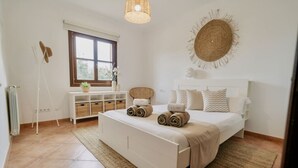 Une chambre à coucher avec un grand lit, une table de chevet, un radiateur, une fenêtre et un luminaire suspendu.