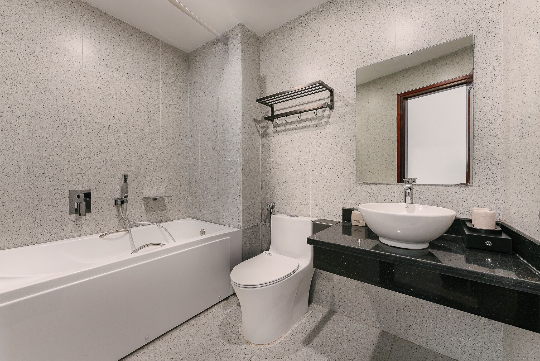 A modern bathroom with a white bathtub, a toilet, and a sink with a black countertop.