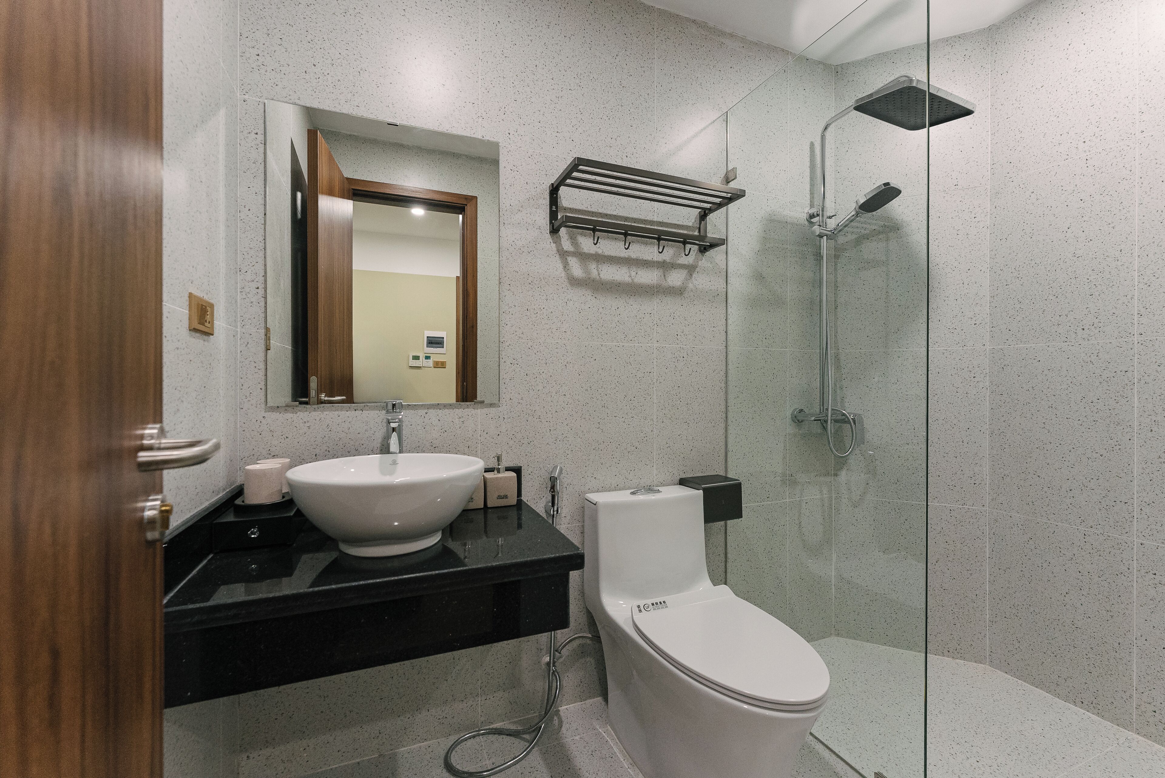 Ein modernes Badezimmer mit einem weißen Waschbecken, einer schwarzen Arbeitsplatte und einer Duschkabine.