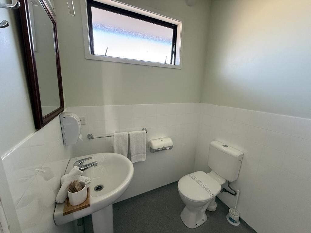 A small bathroom with a sink, toilet, and window.