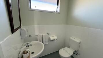A small bathroom with a sink, toilet, and window.