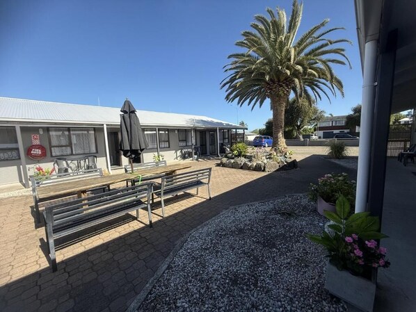 A building with a covered outdoor seating area, a palm tree, and a fire hydrant.