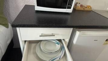 A kitchen area with a microwave on a black countertop, a white cabinet below, and a dishwasher to the right.
