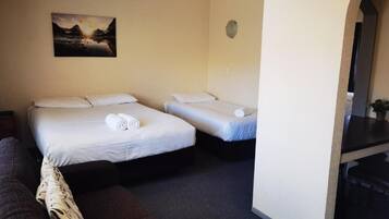 A room with two single beds, a sofa, a painting on the wall, and a small table.